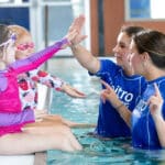 Swim instructors teaching children to swim