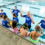 Swim instructors teaching children to swim