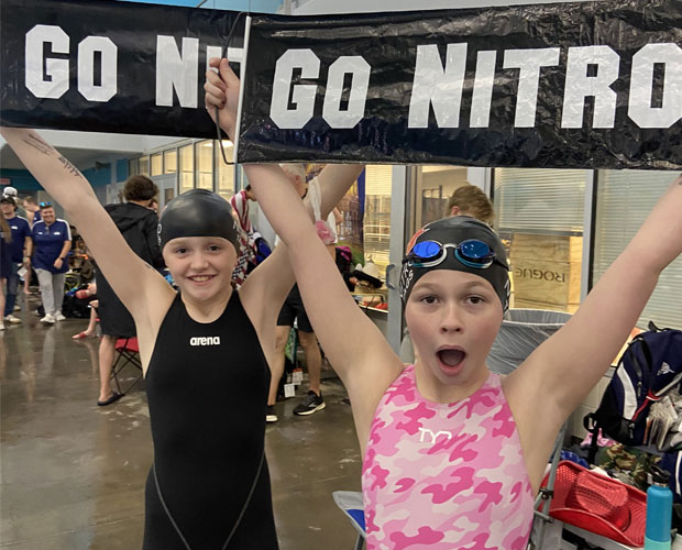 Kyle swim team members with banner